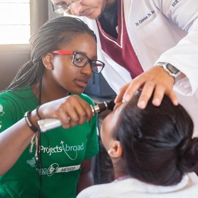 A Projects Abroad intern assists with checking a patient to gain internship work experience overseas. 